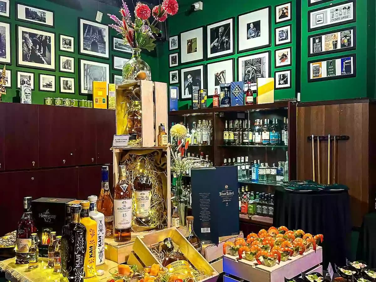 A vibrant bar setup with premium liquor display, floral decor, and hors d'oeuvres