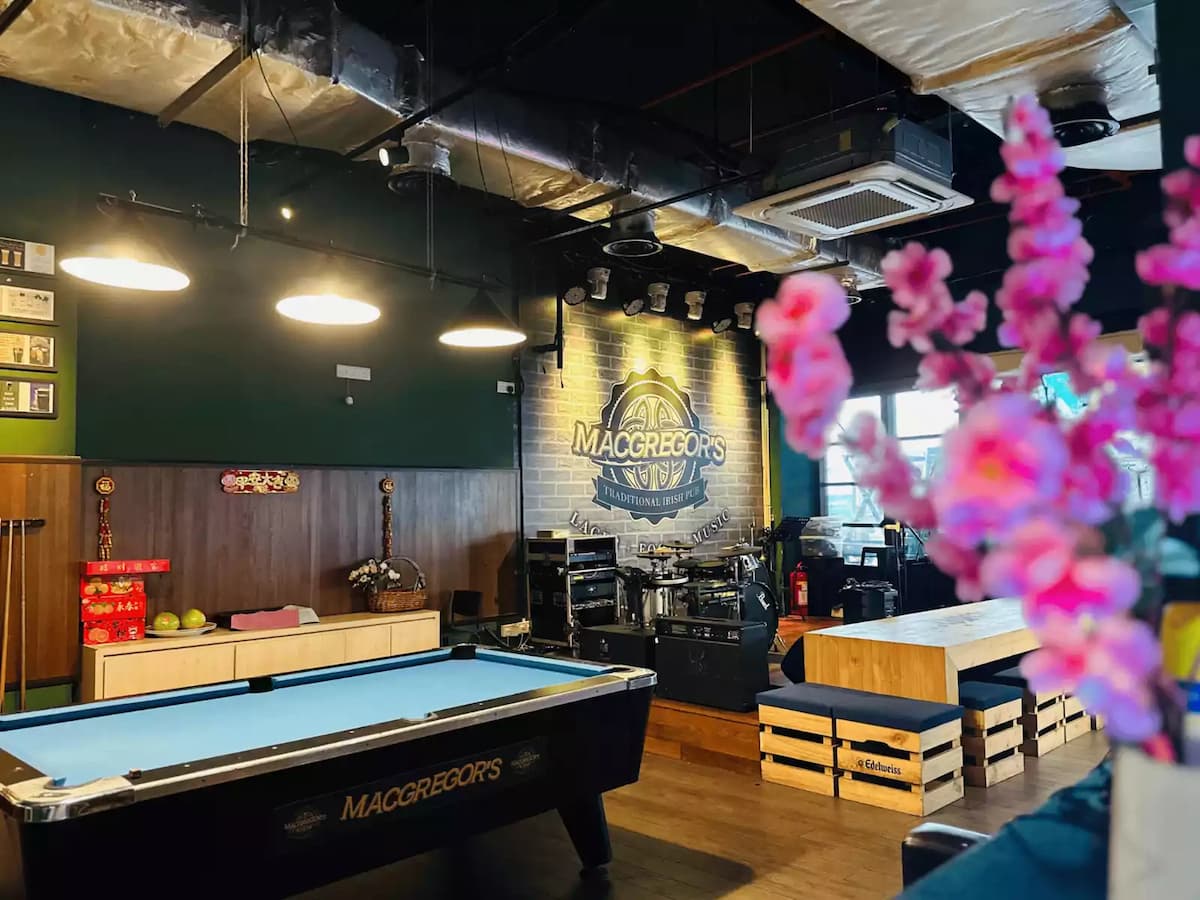 A stylish pub interior featuring a pool table, stage setup, and casual seating