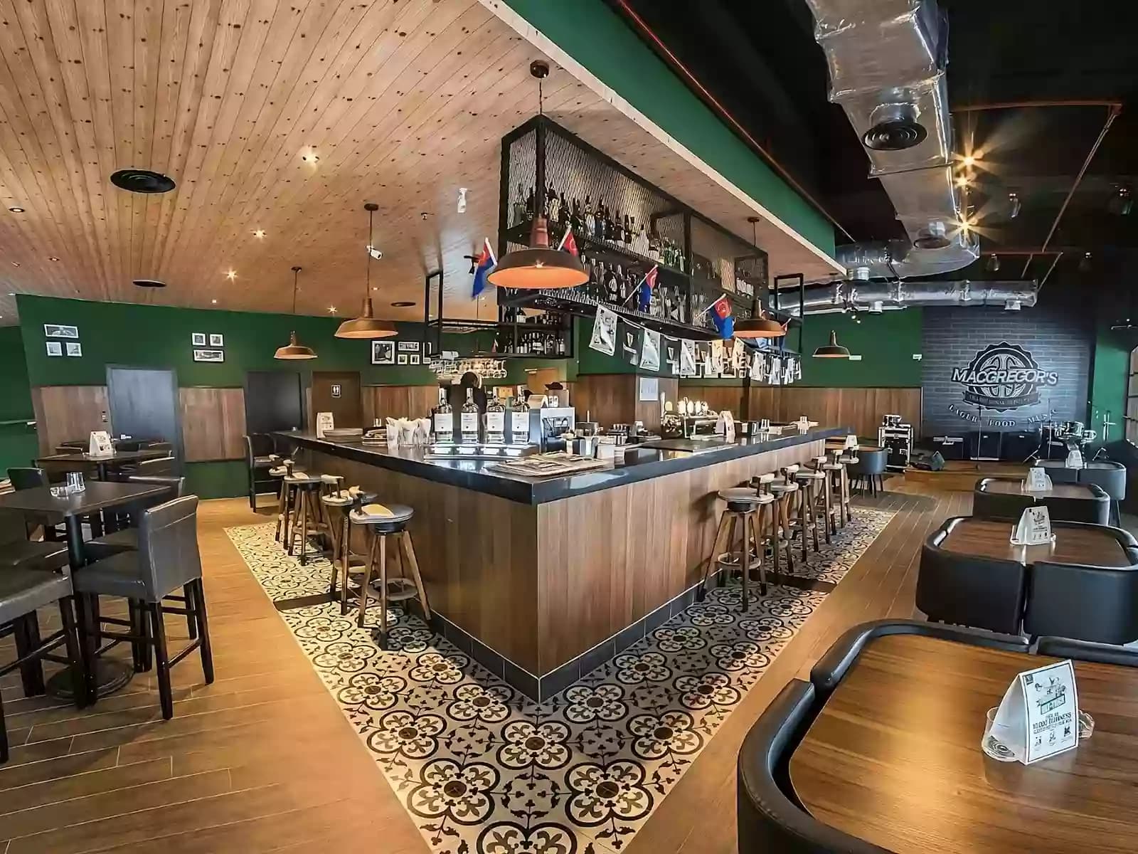 A spacious and stylish bar with central counter seating, cozy booths, and modern pub décor