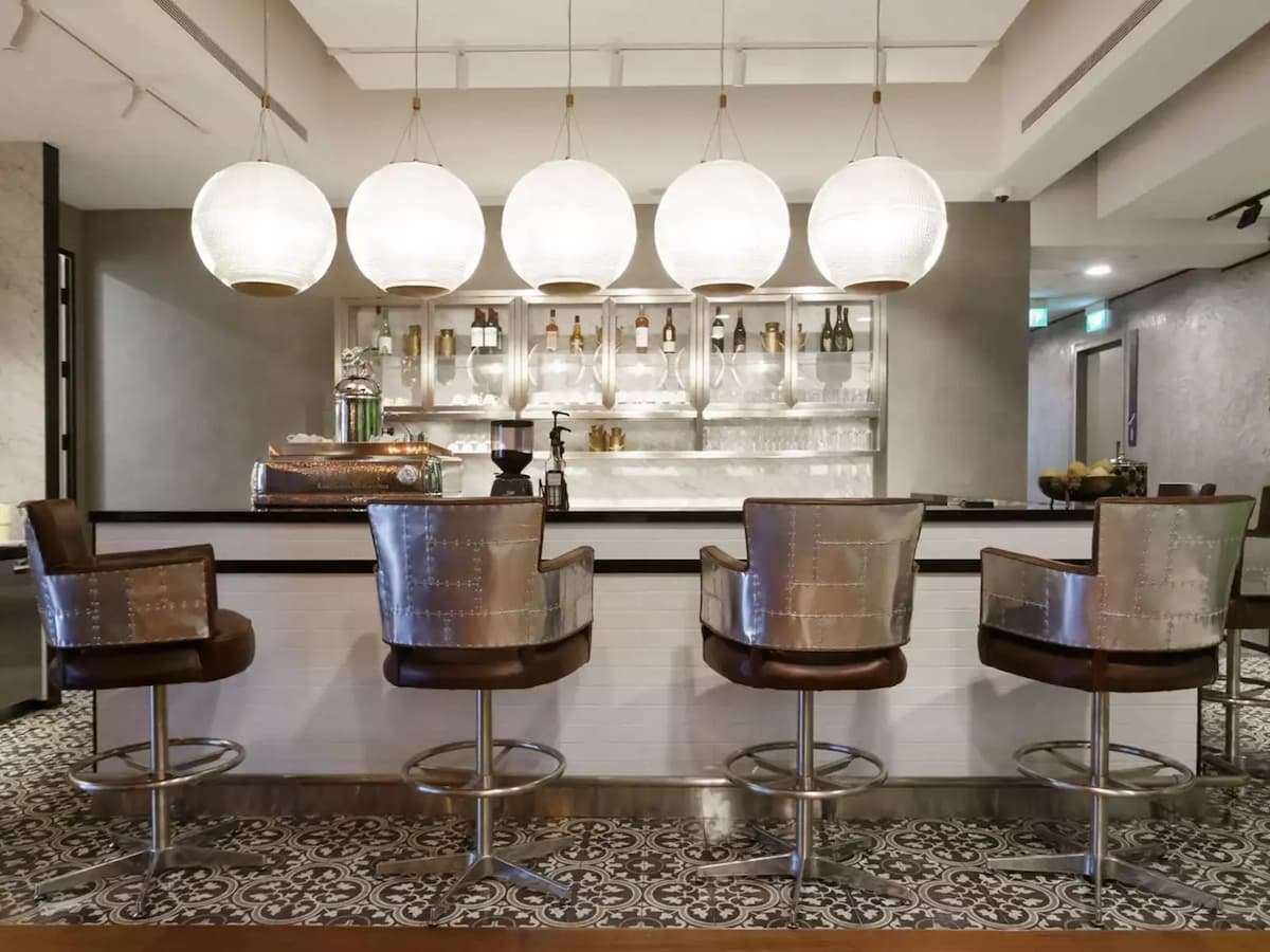 Contemporary bar lounge with stylish seating and illuminated pendant lights.
