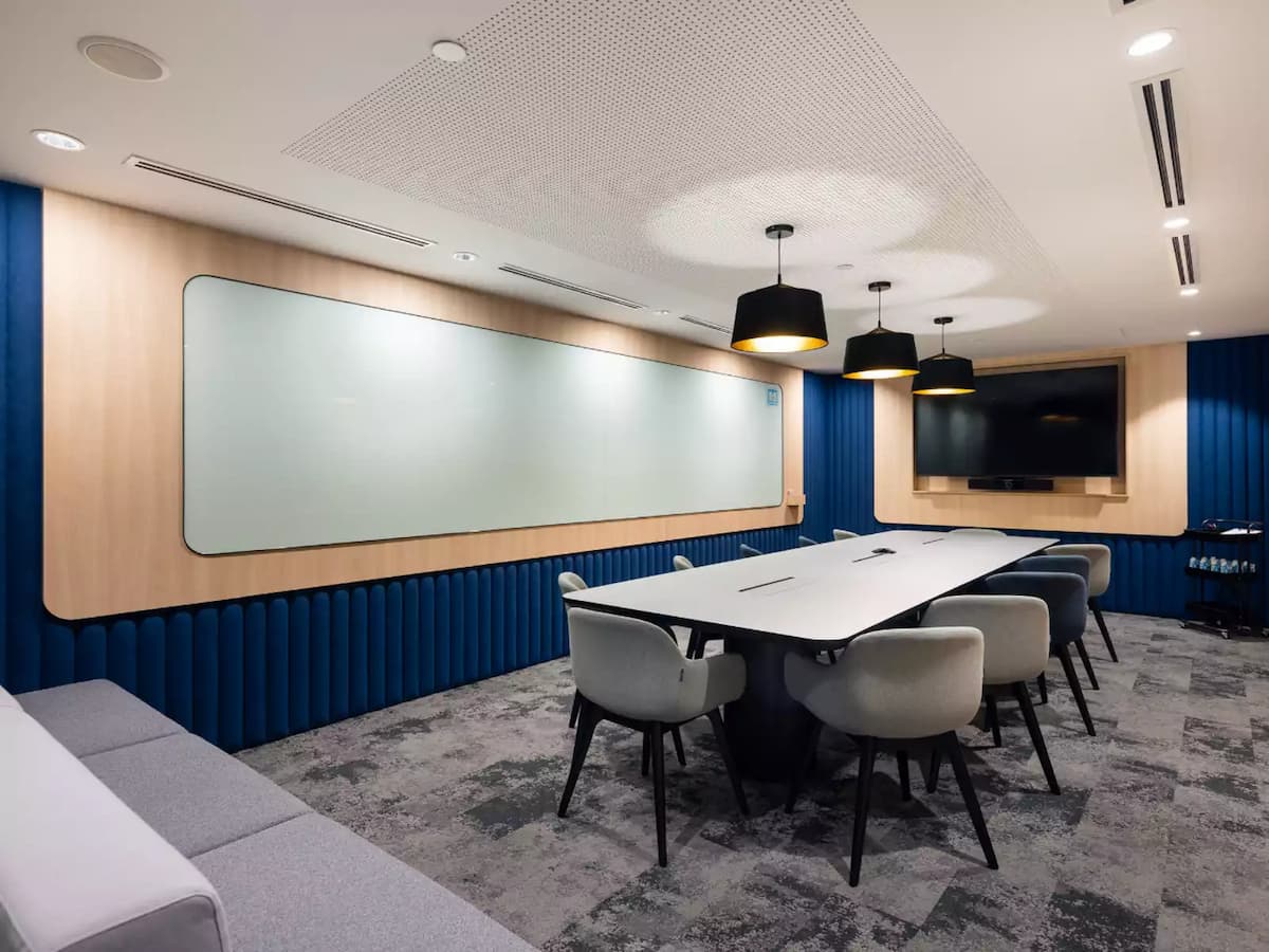 Modern meeting room with conference table, whiteboard, and screen display.