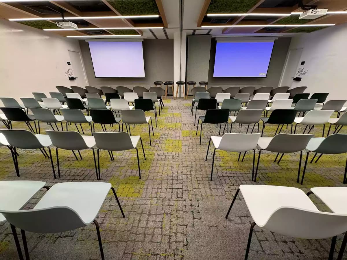 Modern seminar room with theater-style seating and dual projection screens.