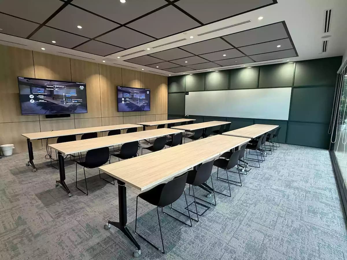 Modern training room with classroom seating and dual presentation screens.