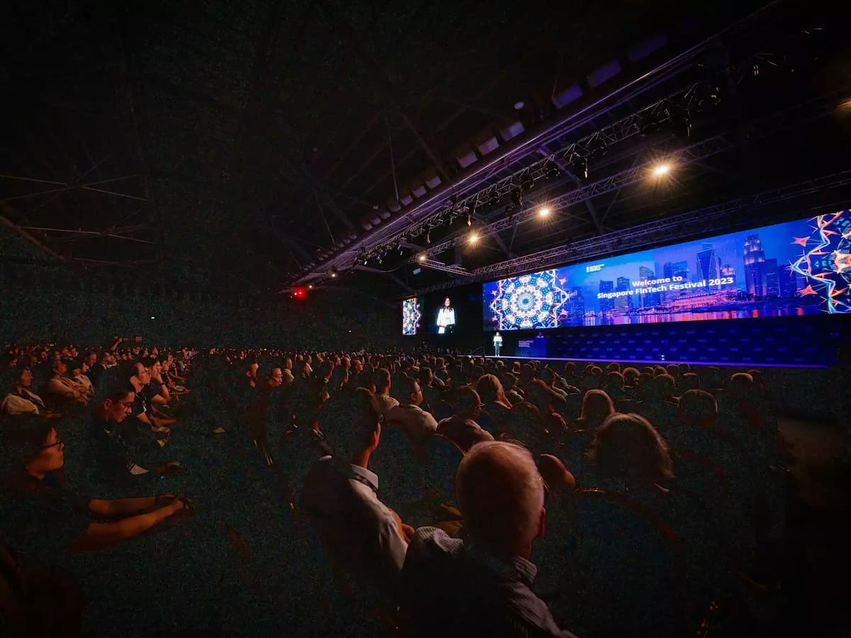 Large audience attending a conference with a speaker on stage.