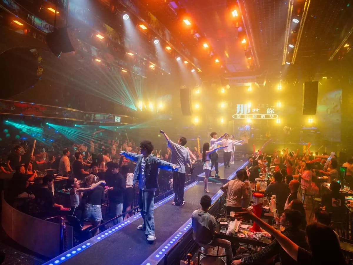 High-energy live entertainment venue featuring a runway stage, vibrant lighting effects, and a lively crowd