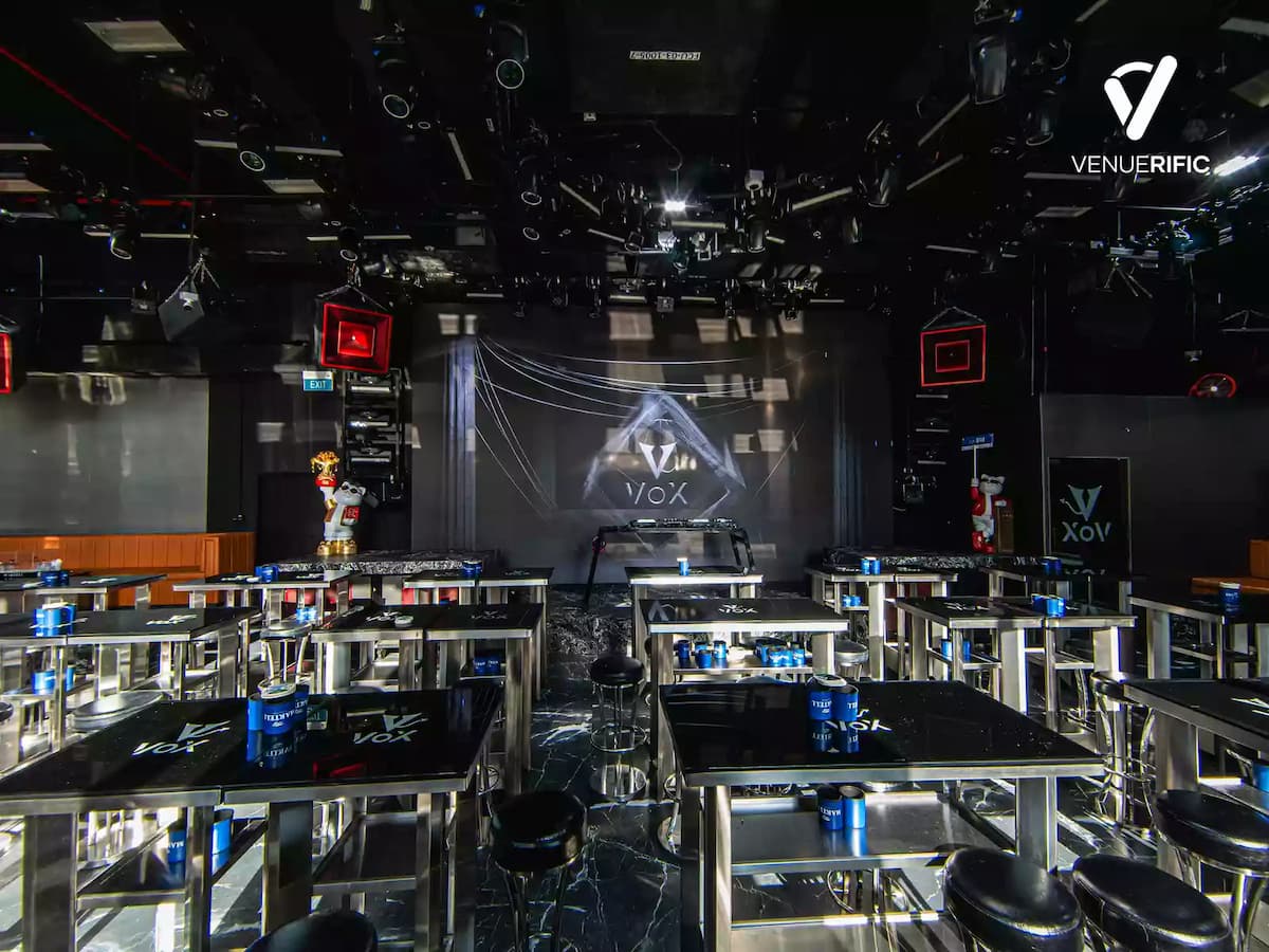 Modern nightclub venue with high tables, stage backdrop screen, and professional lighting setup.