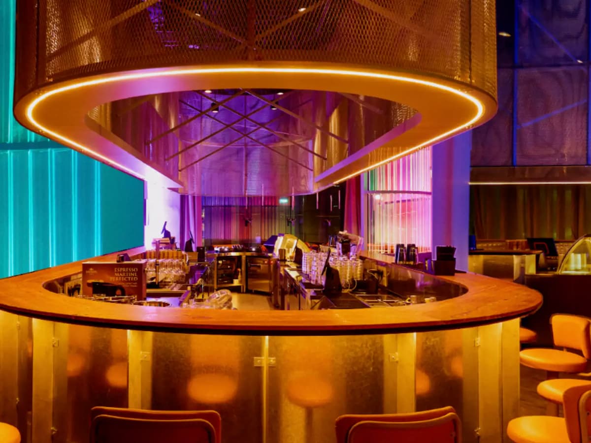 Circular bar counter with warm amber lighting, overhead ring fixture, and modern lounge seating.