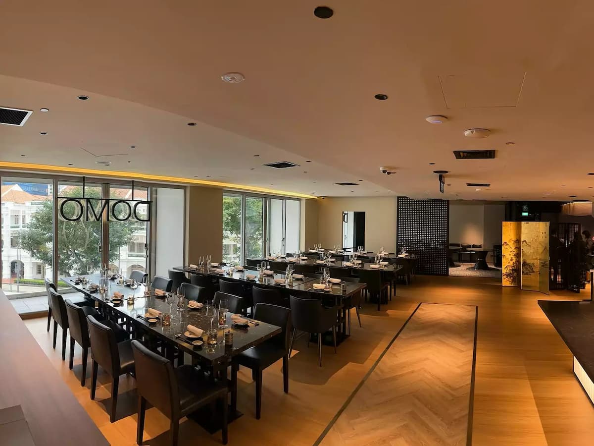 Modern restaurant-style event space with long dining tables and city views.