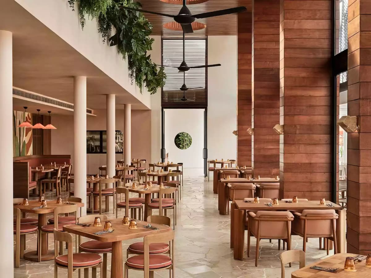 Elegant restaurant interior with wooden finishes, high ceilings, and neatly set dining tables.
