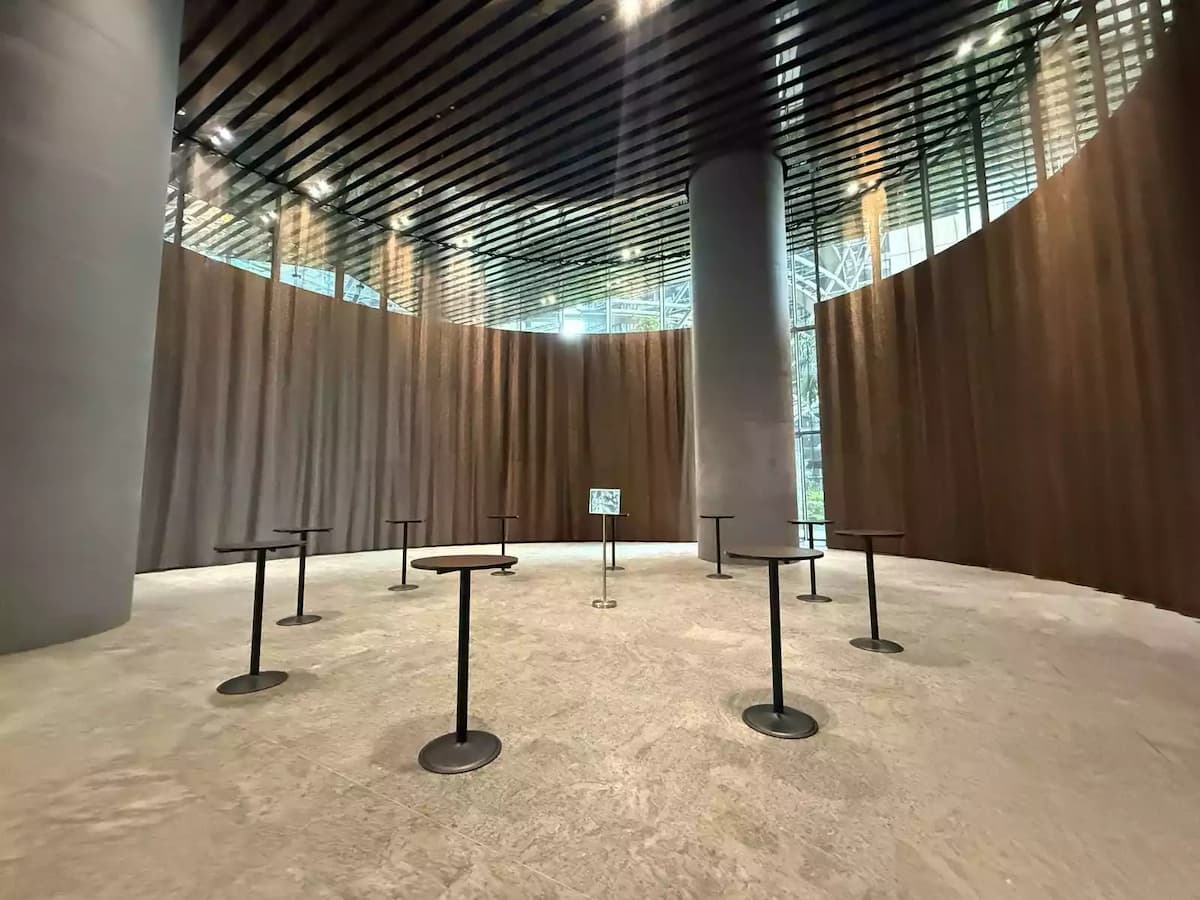 Circular event space with cocktail tables, draped walls, and high ceiling.