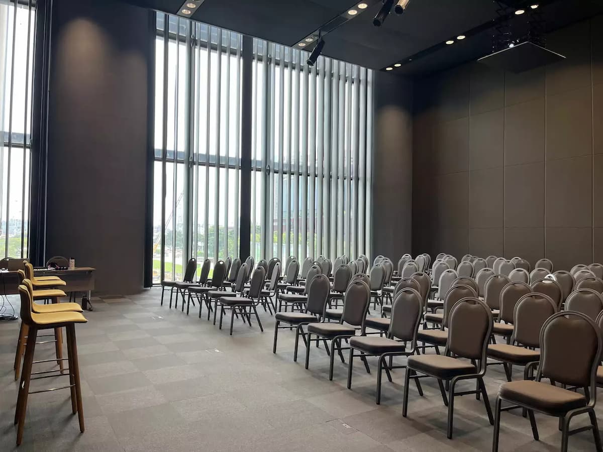 Modern conference room with theatre seating, tall windows, and stage setup.