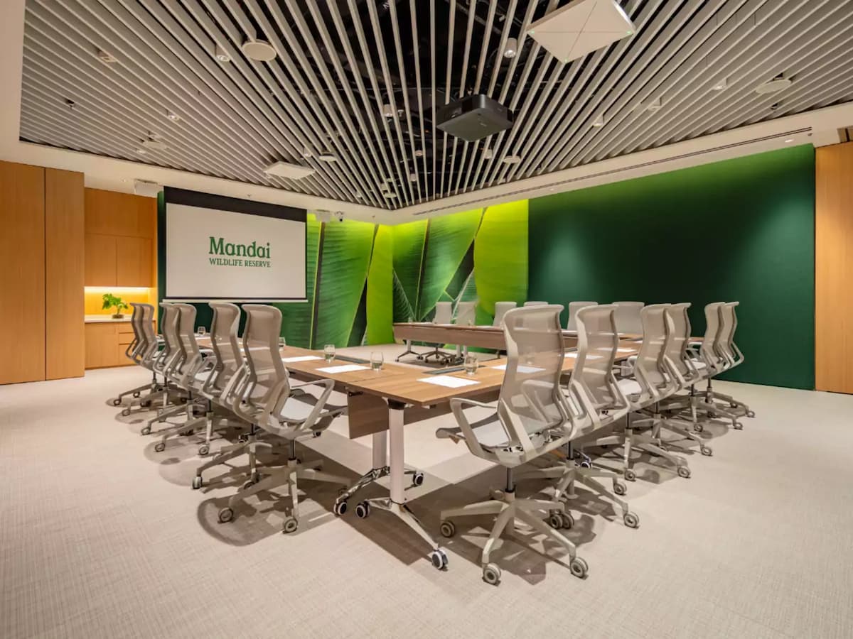 Modern boardroom with conference table, ergonomic chairs, and presentation screen.