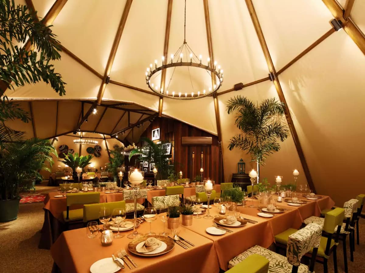 Elegant tented dining venue with chandelier lighting and lush greenery.