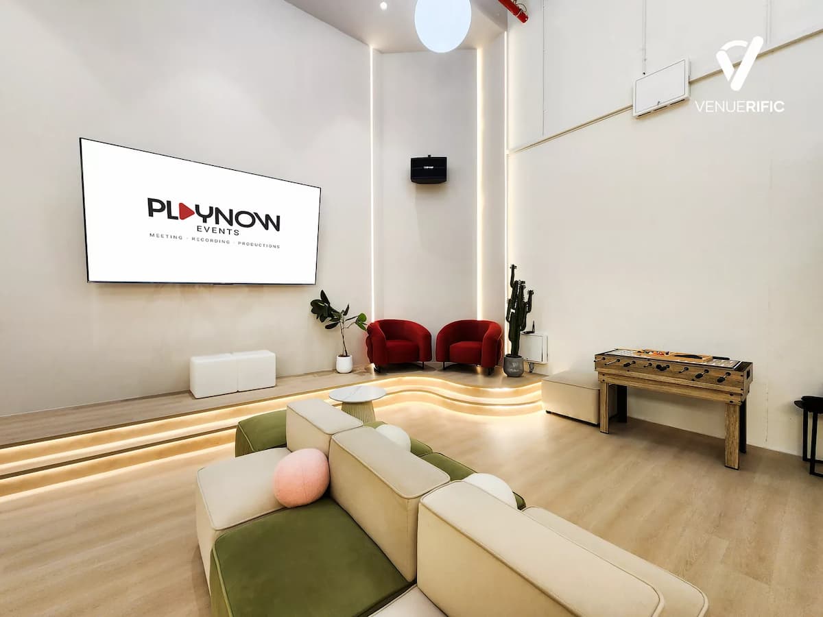 Minimalist event studio with modular seating, presentation screen, and soft lighting.