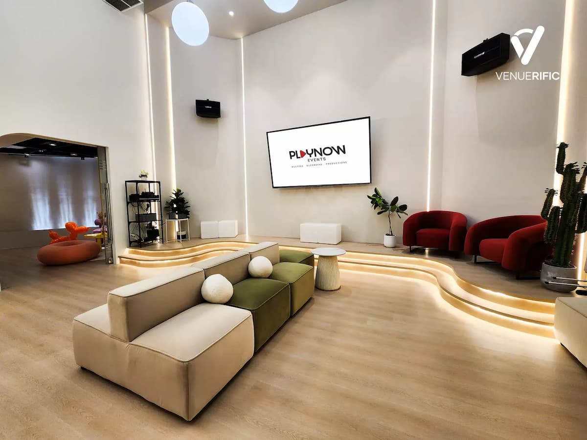 Minimalist event studio with modular seating, presentation screen, and ambient lighting.