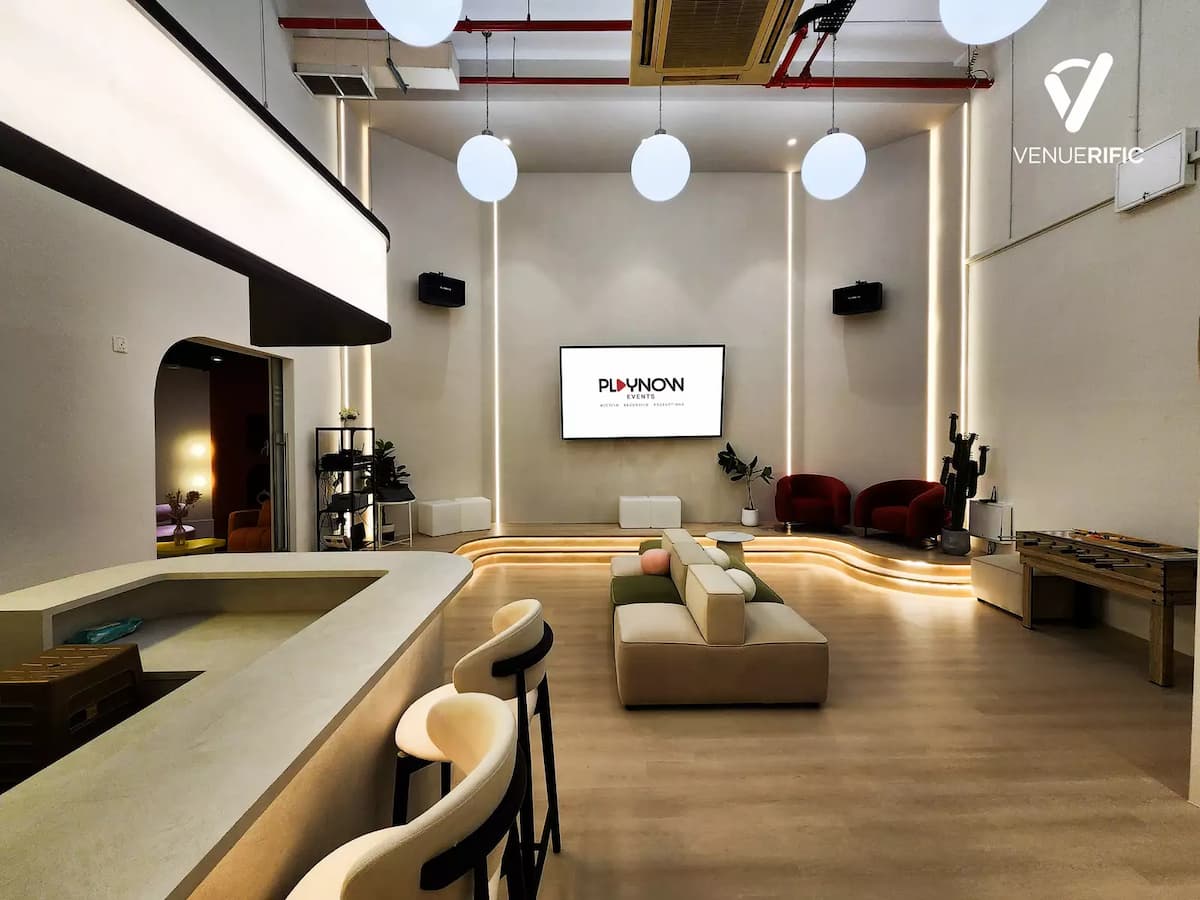 Minimalist event studio with bar counter, modular seating, and presentation screen.