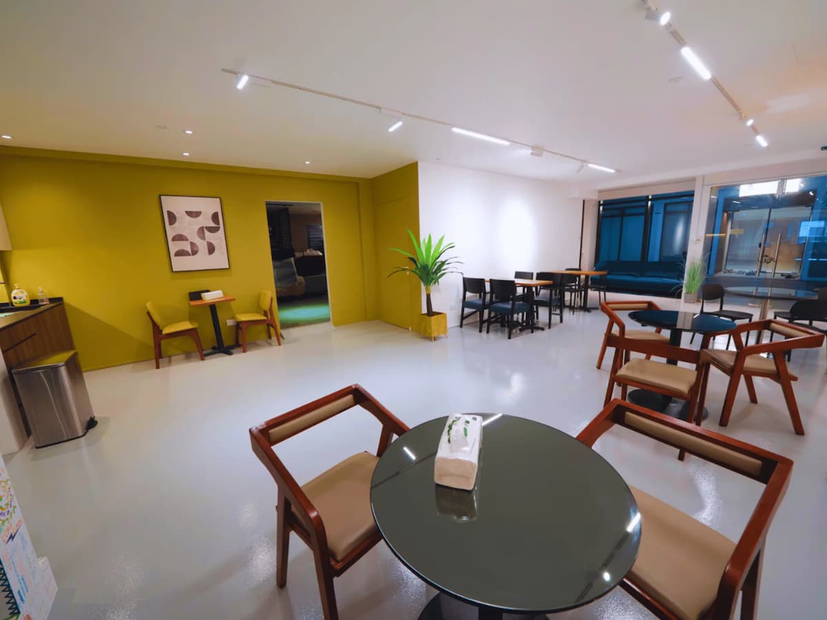 Bright modern dining space with round tables, wooden chairs, and a mustard accent wall.