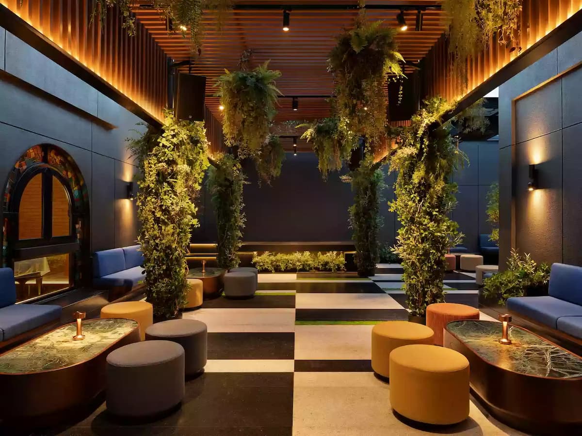 Stylish indoor lounge with blue seating, hanging greenery, warm accent lighting, and modern tiled flooring.