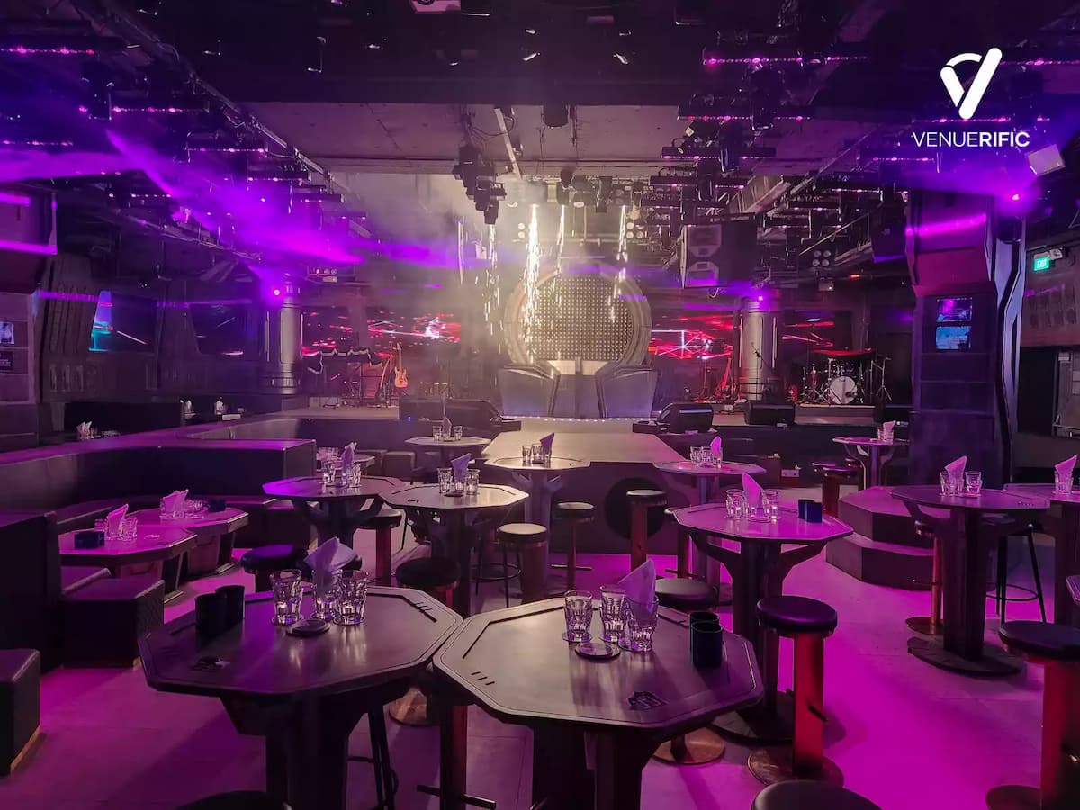 venue with stage, table seating, and purple ambient lighting.