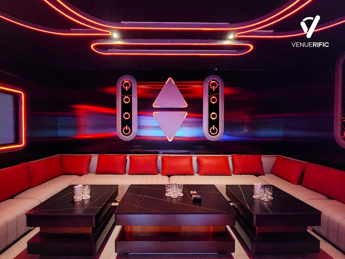 Sleek lounge with red neon accents, long white sofas with red pillows, and futuristic wall art.