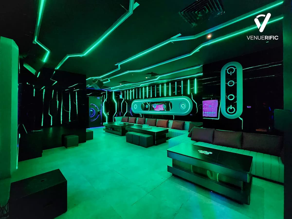 Futuristic lounge with teal neon geometric lighting and a U-shaped sofa.
