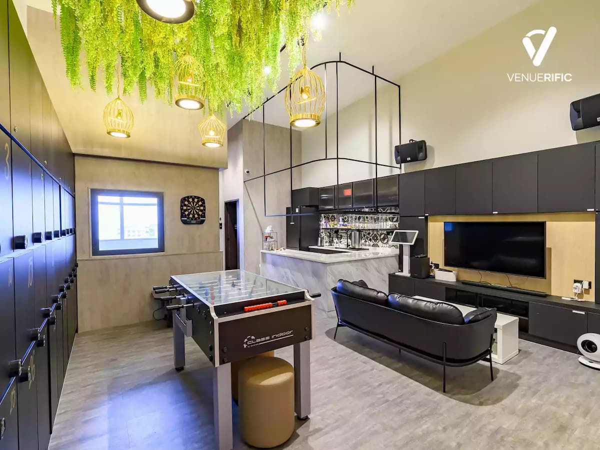Stylish social lounge with foosball table, bar counter, greenery ceiling accents, and relaxed seating.