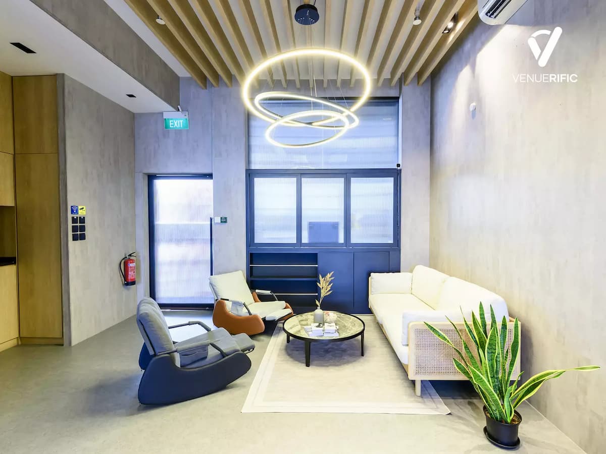 Contemporary lounge area with sofa seating, accent chairs, circular pendant lights, and a calm, modern atmosphere.