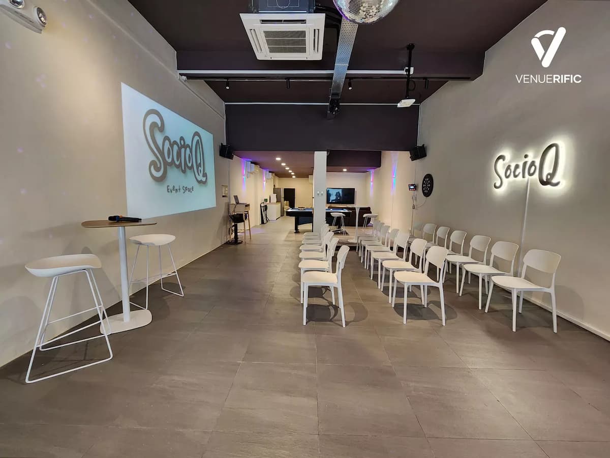 theatre-style seating with white chairs, projector screen displaying the SocioQ logo, minimalist concrete walls