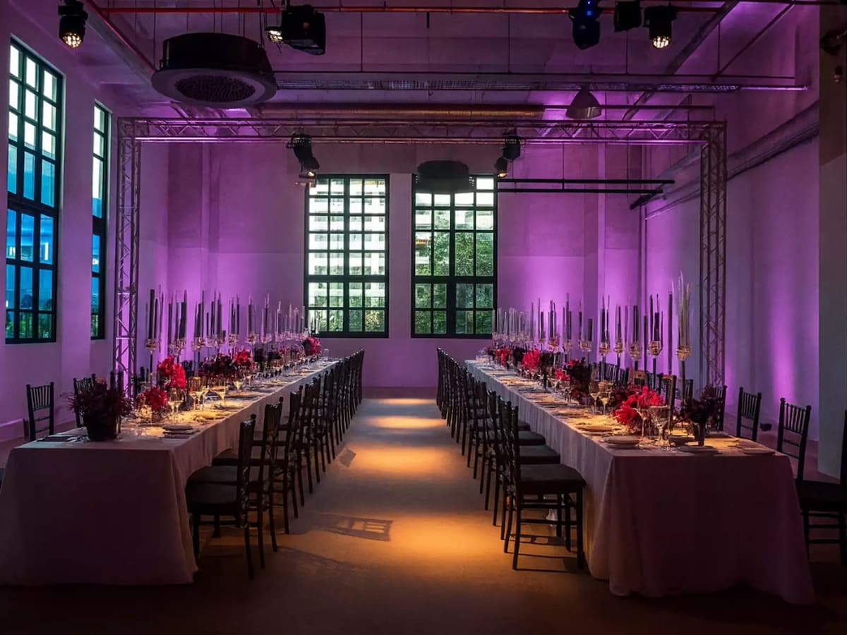 Long banquet tables set for a formal dinner with purple ambient lighting.