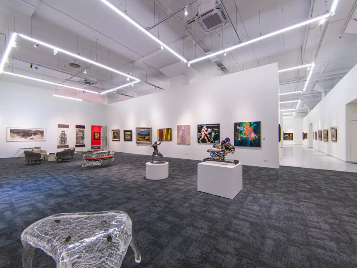 Contemporary art gallery with paintings, sculptures, and open layout.
