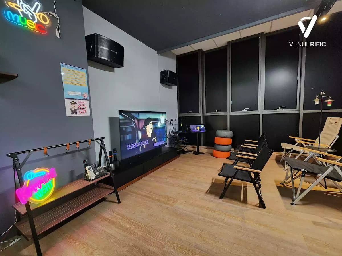 Casual entertainment room with lounge chairs, TV setup, neon accents, and a relaxed, social atmosphere.