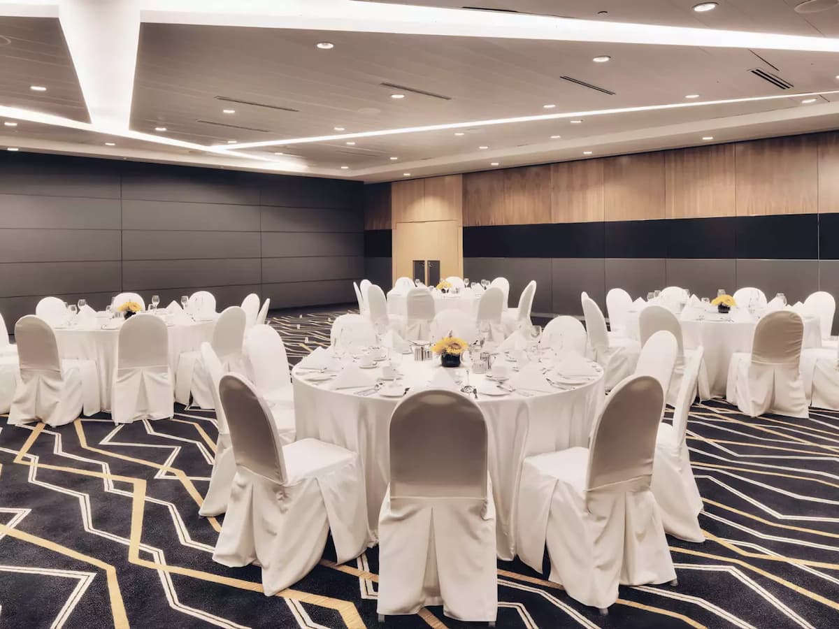 Elegant ballroom set with round dining tables and white banquet chairs.