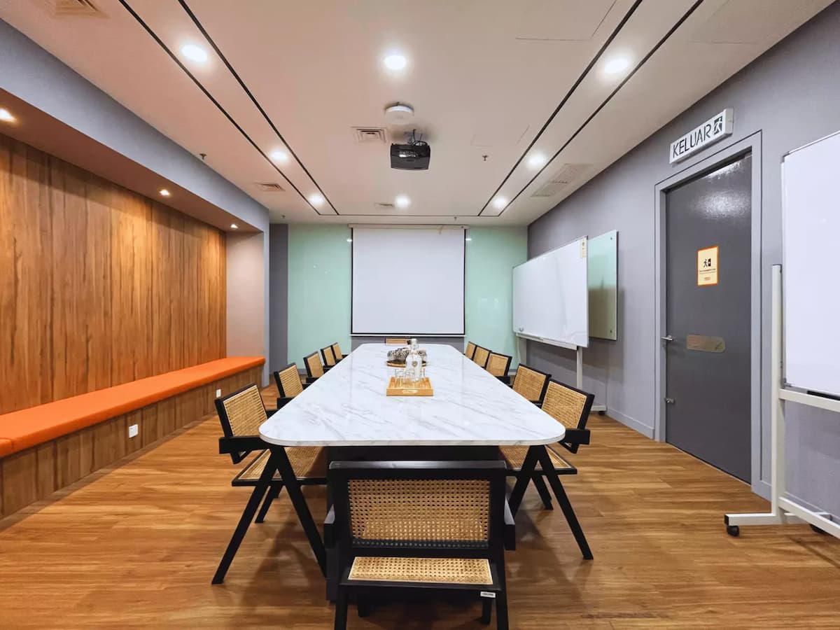 long marble meeting table with rattan chairs facing a projector screen in a corporate training room at kl sentral kuala lumpur