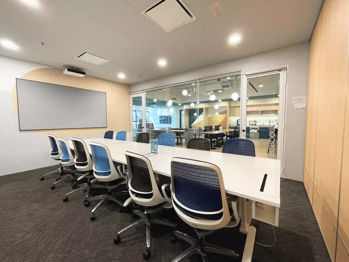 long white boardroom table with twelve blue chairs and a projector whiteboard at a corporate meeting space in kl eco city kuala lumpur