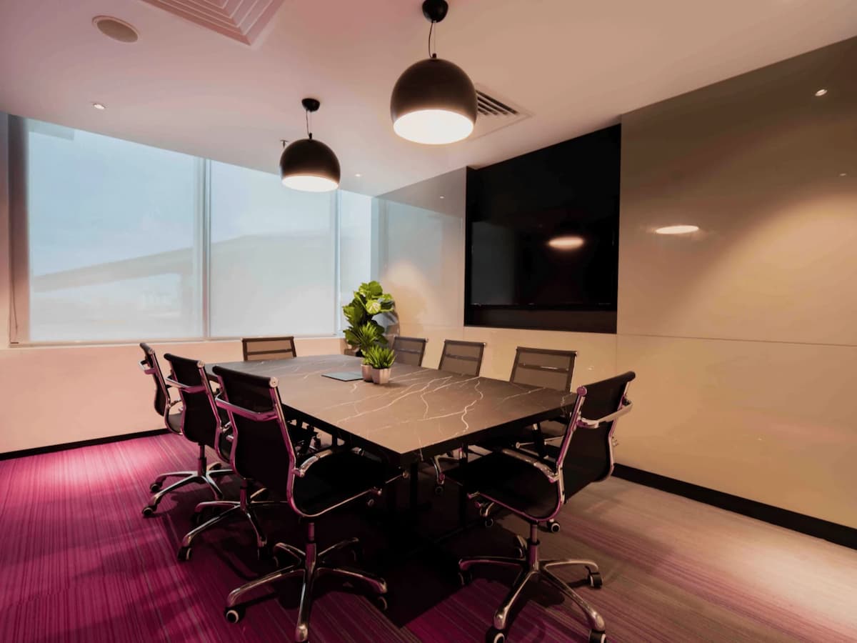 marble meeting table with eight chairs and pendant lights in a small pink carpeted meeting room for team discussions in kuala lumpur