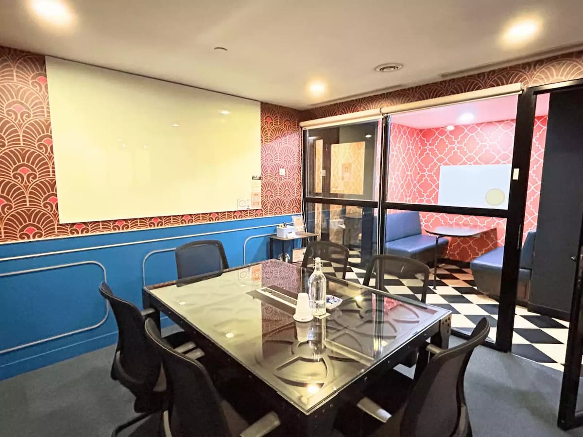 colourful meeting room with glass top table six chairs writing board and a blue sofa lounge beside it in bangsar south kuala lumpur
