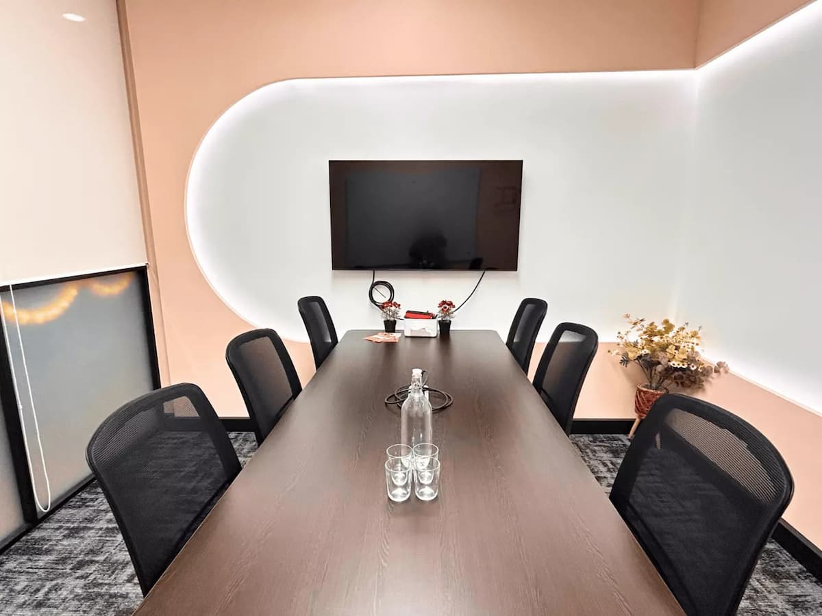private peach meeting room with dried flowers water glasses and a tv screen at bangsar versatile meeting seminar venue affordable event space in bangsar kuala lumpur