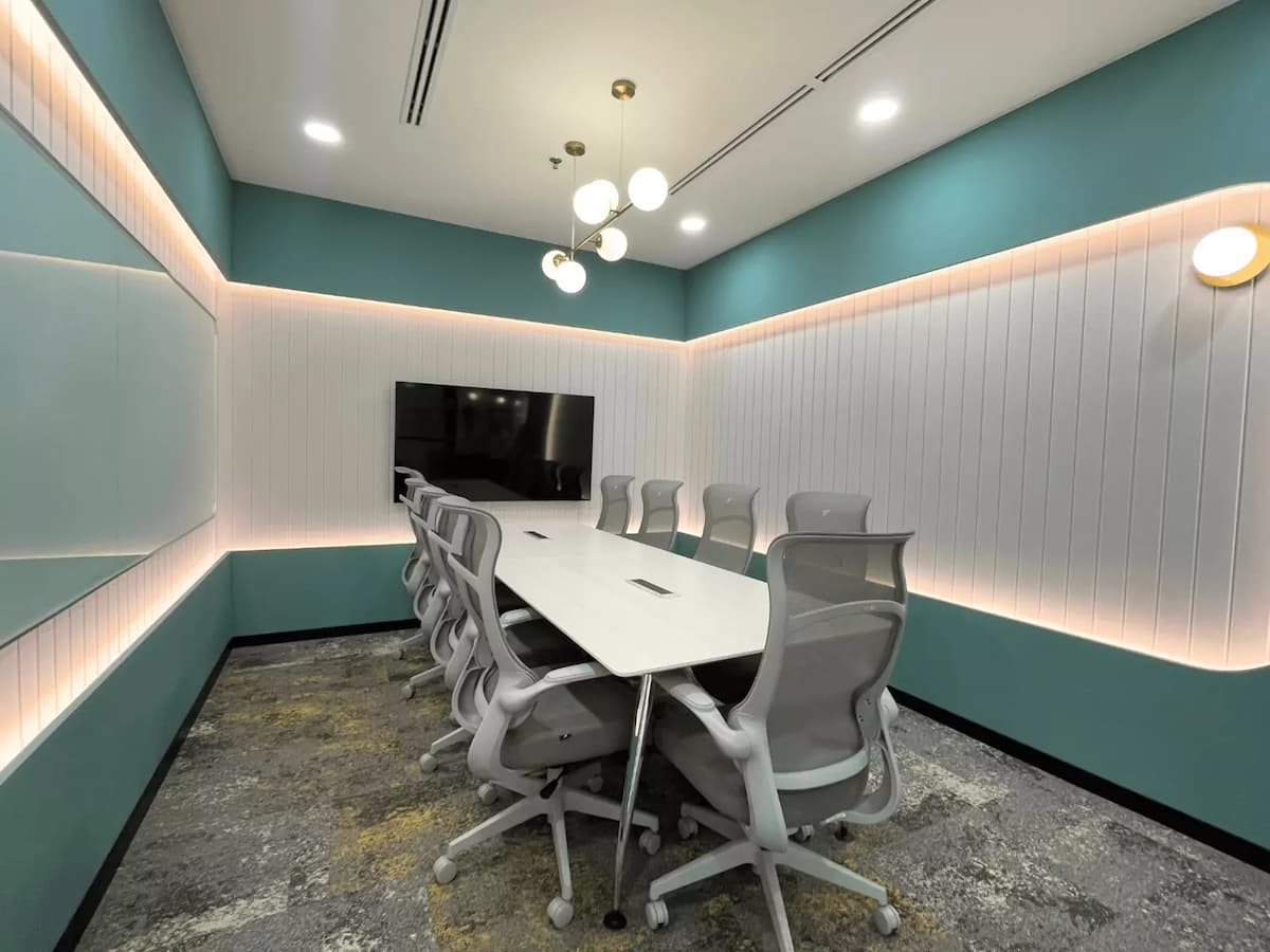 teal boardroom with long white table ten mesh chairs and wall mounted tv screen at worq bandar utama corporate meeting space in petaling jaya