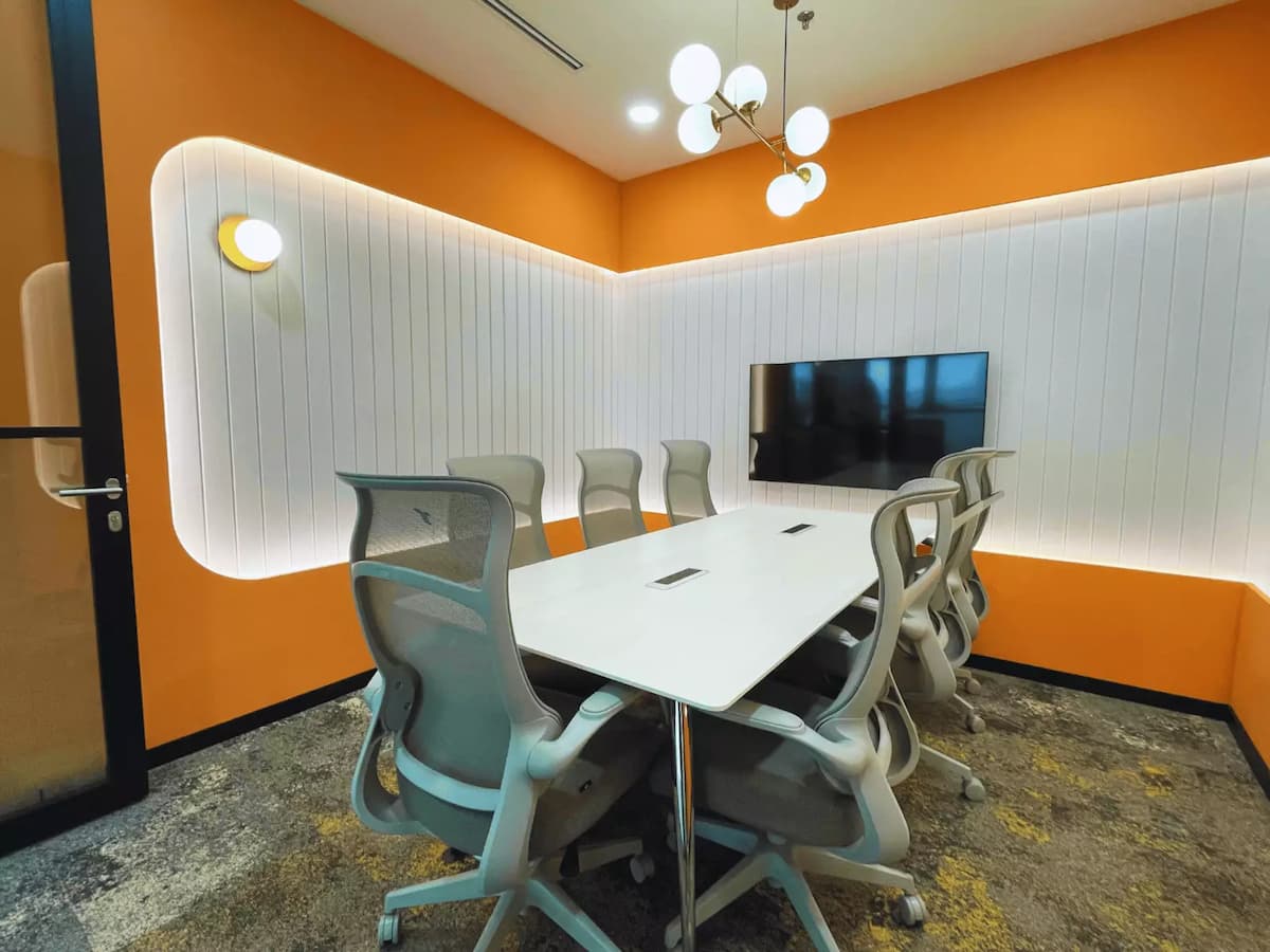 orange private meeting room with eight ergonomic chairs and tv screen for team strategy sessions at worq bandar utama petaling jaya