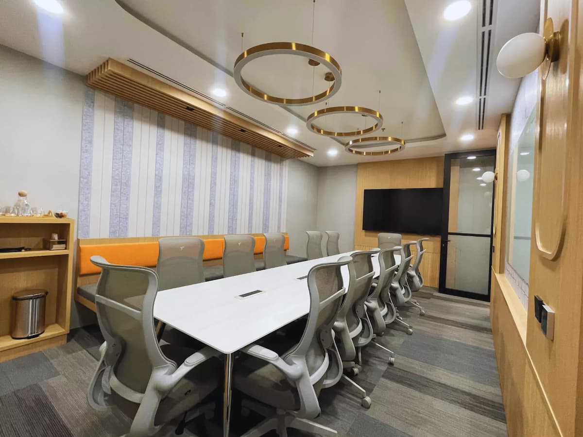 twelve seater board meeting room with gold ring pendant lights orange bench seating and tv screen at worq bandar utama in kpmg tower petaling jaya