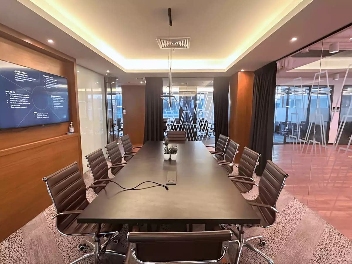 wall mounted presentation screen facing a ten seat conference table in a meeting room for rent near klcc kuala lumpur
