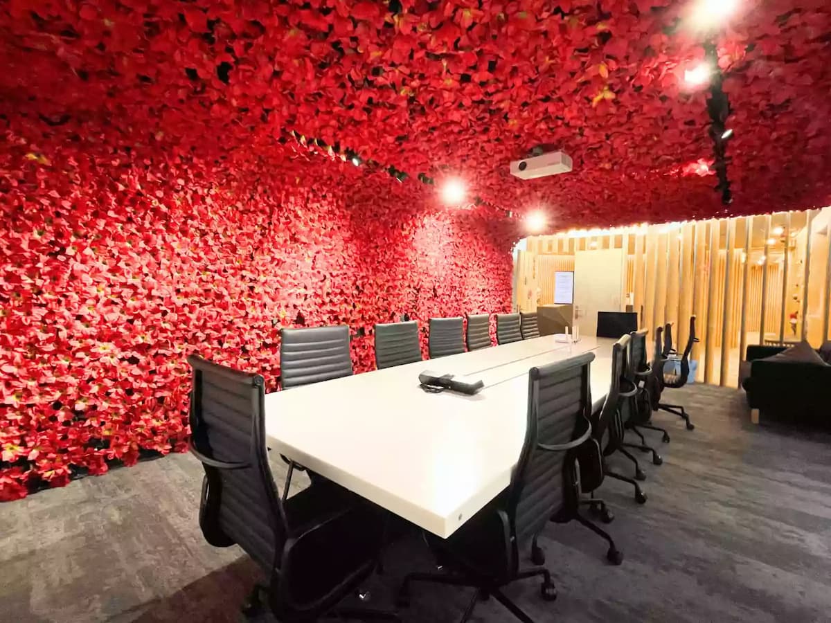 long white boardroom table with black leather chairs surrounded by red flower walls and ceiling at a premium meeting room in bukit bintang kuala lumpur