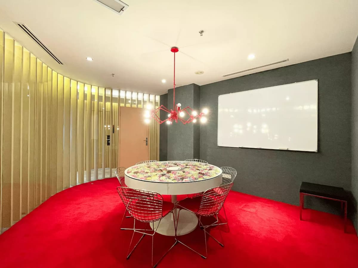 round flower topped table with wire chairs red carpet and whiteboard in a small discussion room at a premium meeting space in bukit bintang kuala lumpur