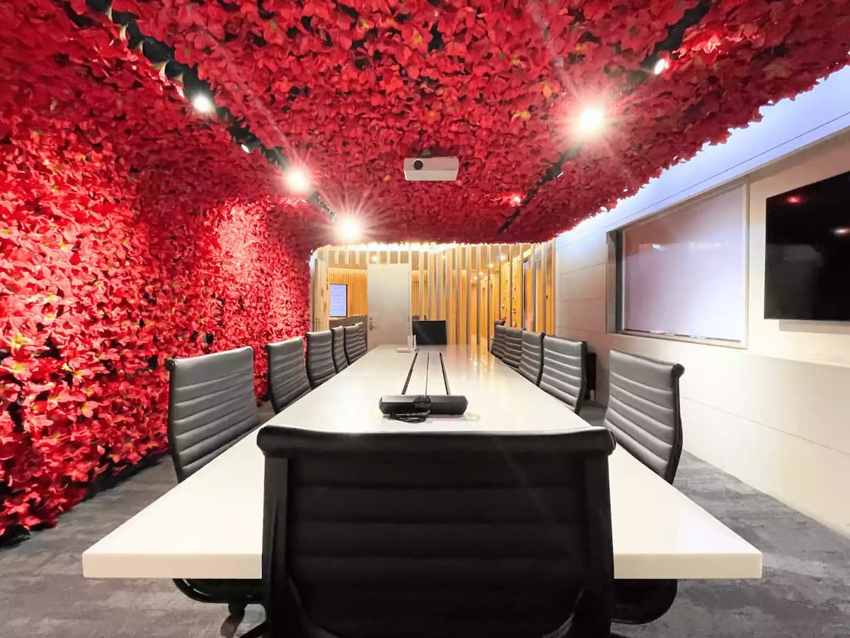 boardroom set up for a business presentation with wall mounted screen whiteboard projector and twelve seats under a red floral ceiling in bukit bintang kuala lumpur