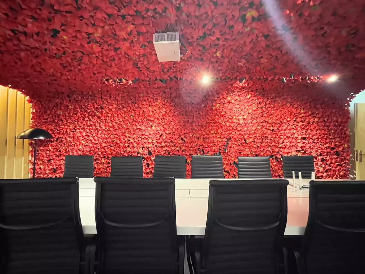 close up of a red flower feature wall behind a white meeting table with high back chairs at a premium event space in bukit bintang kuala lumpur