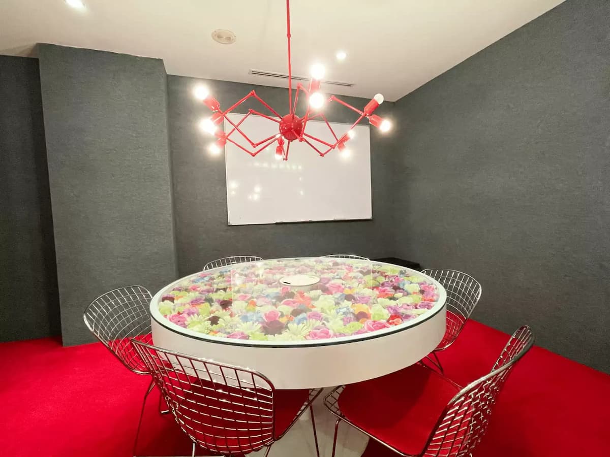 six seat round table with preserved flowers under glass a red spider chandelier and whiteboard in a small brainstorming room in bukit bintang kuala lumpur