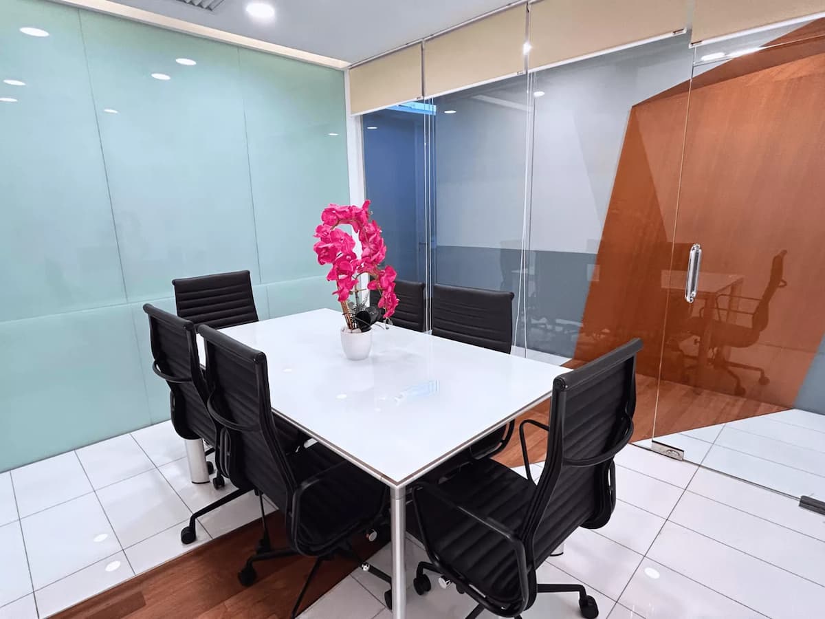 Meeting room with white table, black chairs, glass walls, and pink orchid centerpiece.