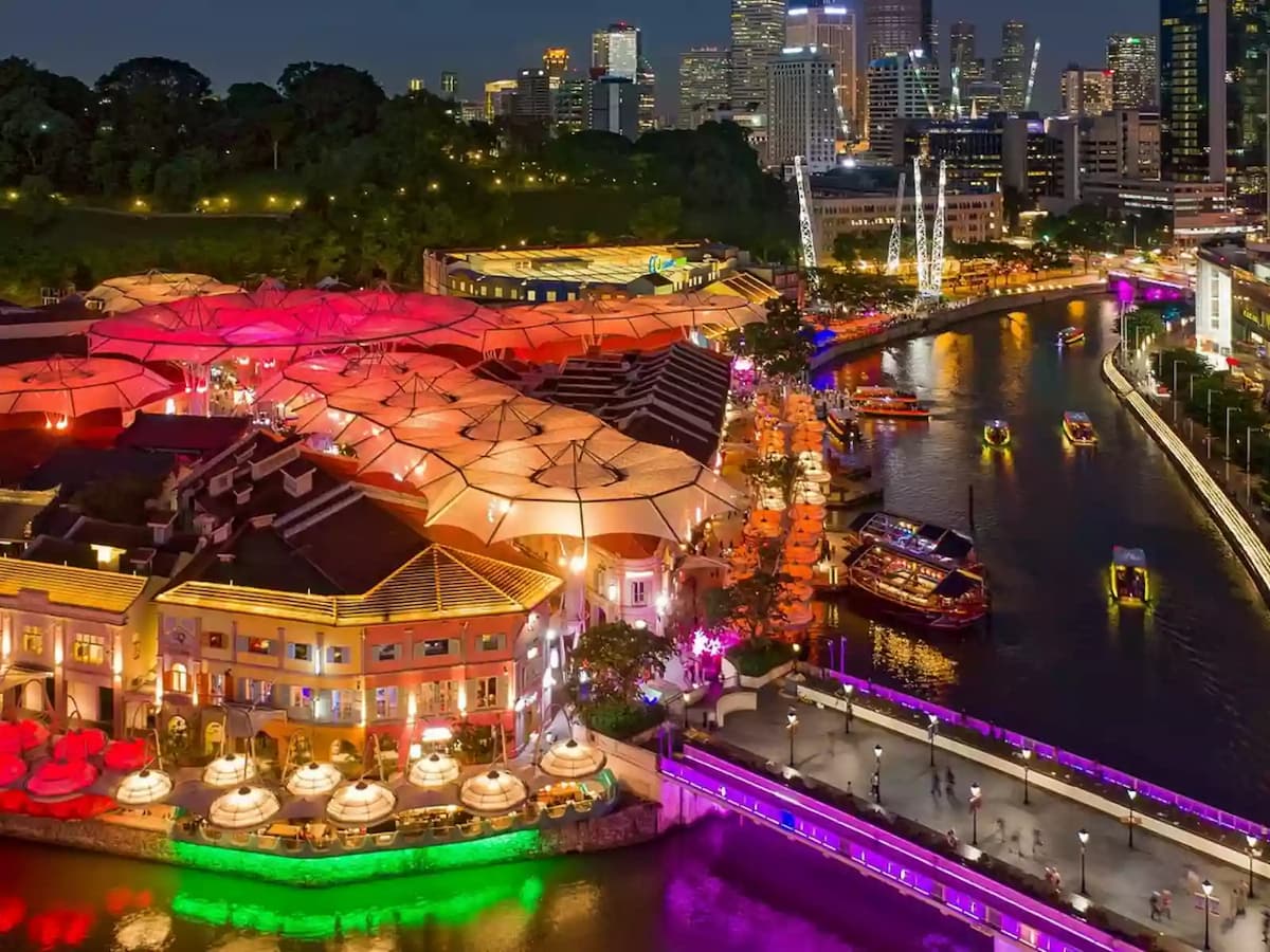 Night view of riverside dining district with colorful lights and city skyline.