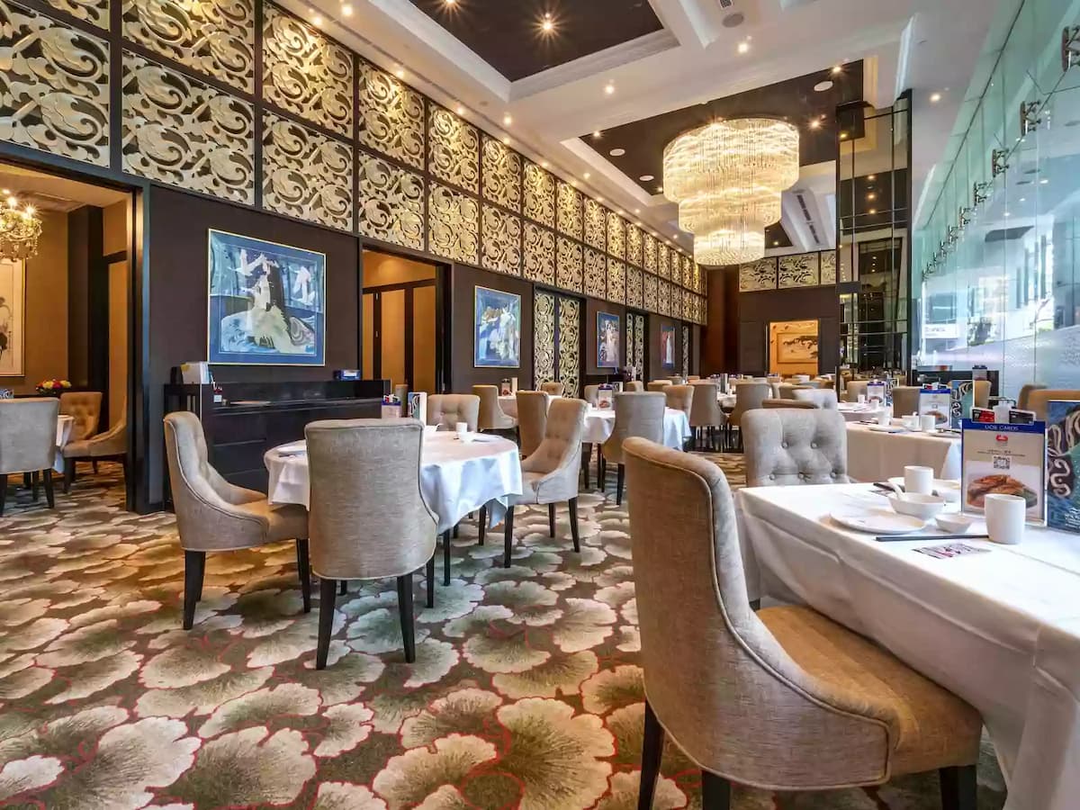 Elegant restaurant dining space with chandelier and patterned walls.