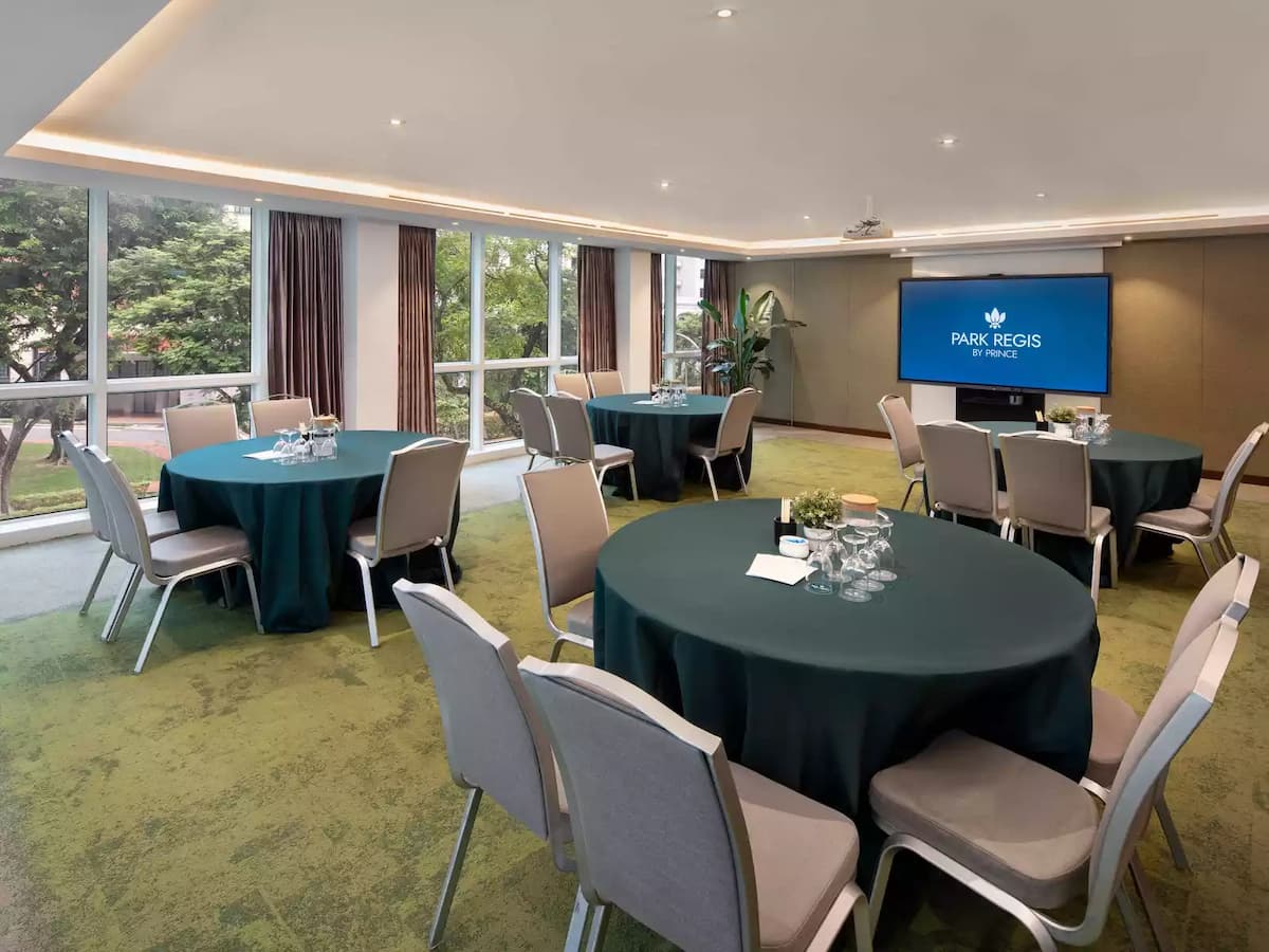 Meeting room with round tables set for discussion and presentation screen.